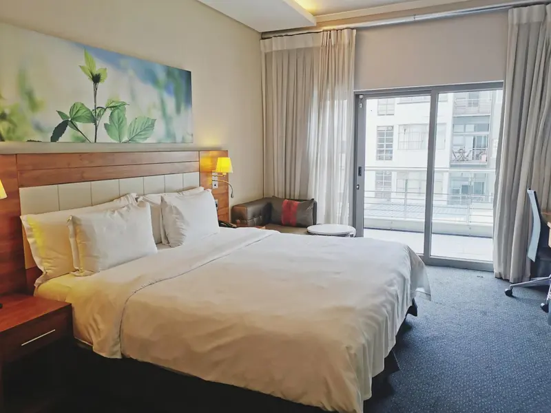 Une chambre lumineuse avec un grand lit et un accès à un balcon.