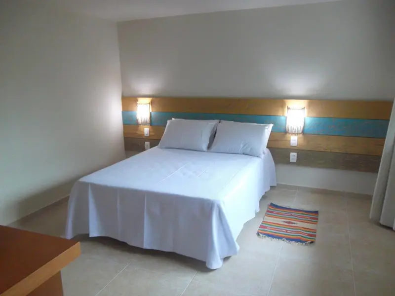 Une chambre lumineuse avec un grand lit recouvert d'une couverture blanche.