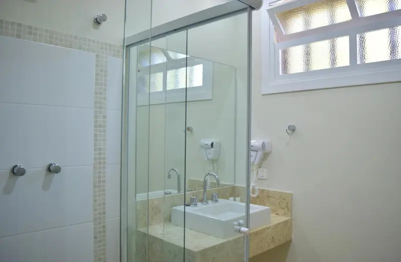 Une salle de bain lumineuse avec une douche vitrée et un lavabo.