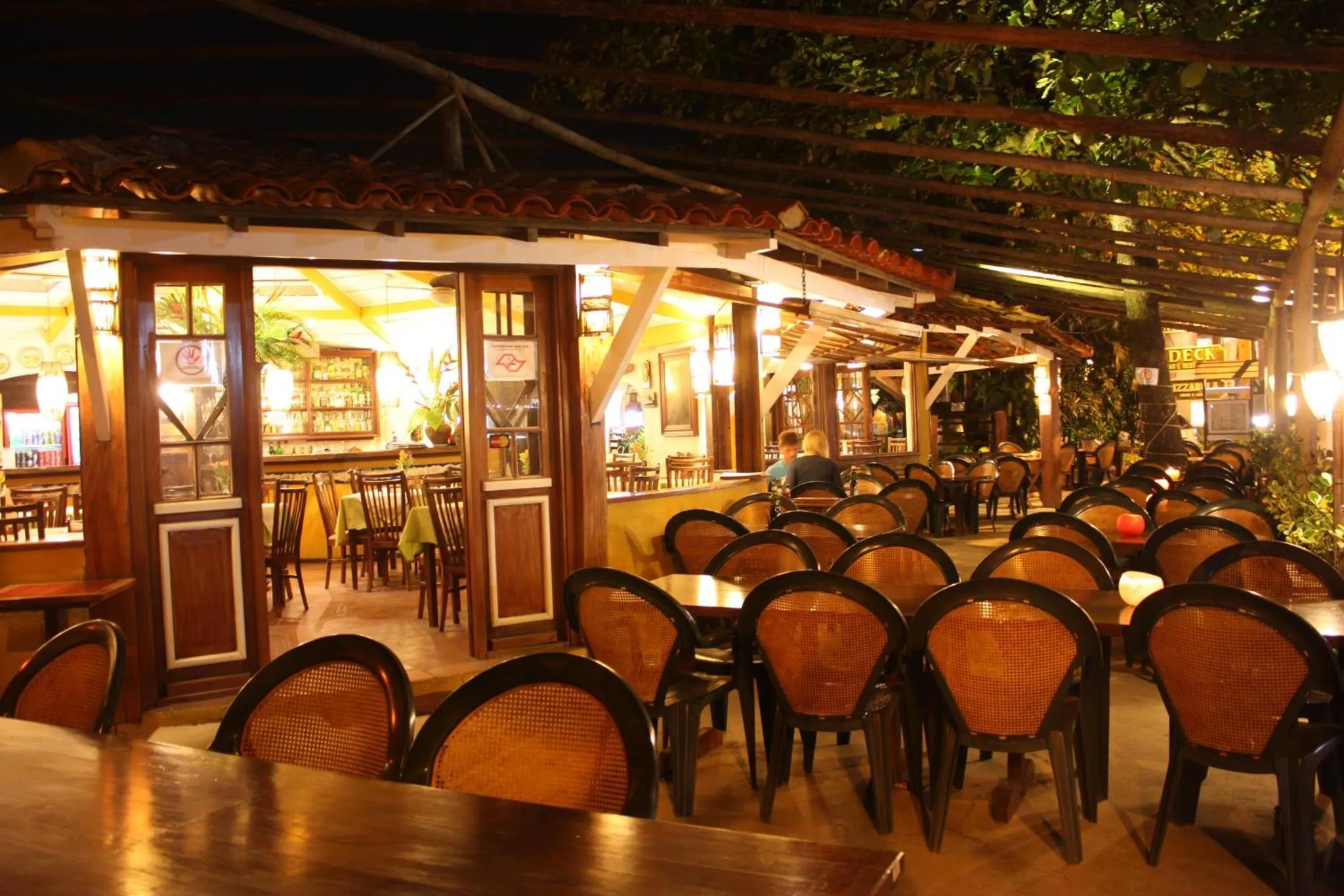 Une salle de restaurant éclairée avec des tables et des chaises.