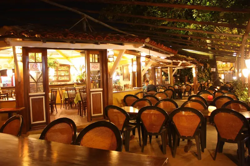 Une salle de restaurant éclairée avec des tables et des chaises.