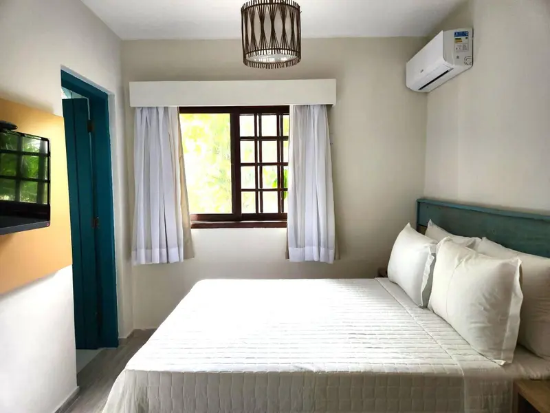 Une chambre lumineuse avec un lit recouvert d'une courtepointe blanche.
