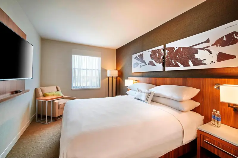 Une chambre lumineuse avec un grand lit et un fauteuil.