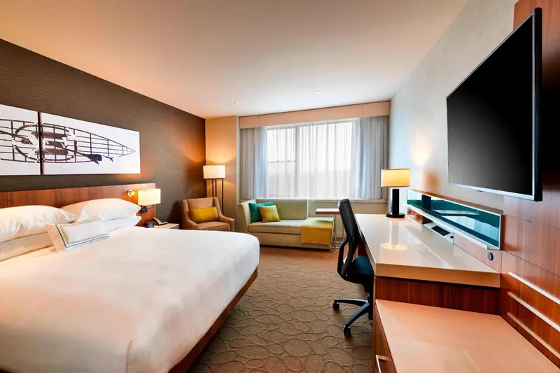 Une chambre d'hotel lumineuse avec un lit, un bureau et un coin salon.