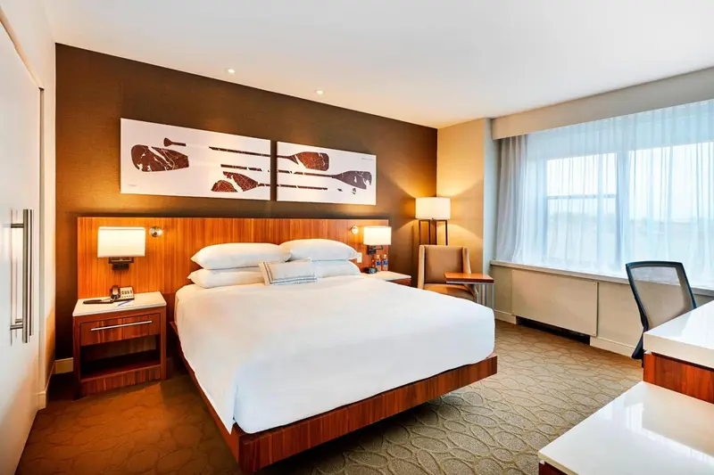 Une chambre d'hôtel lumineuse avec un grand lit recouvert d'une courtepointe blanche.