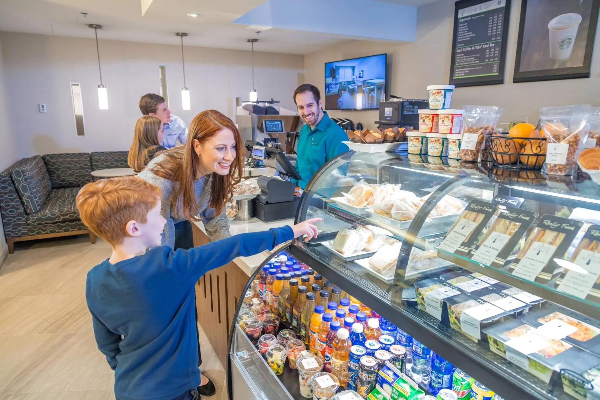 Une cliente et son enfant choisissent des viennoiseries et des boissons au comptoir d'un café.