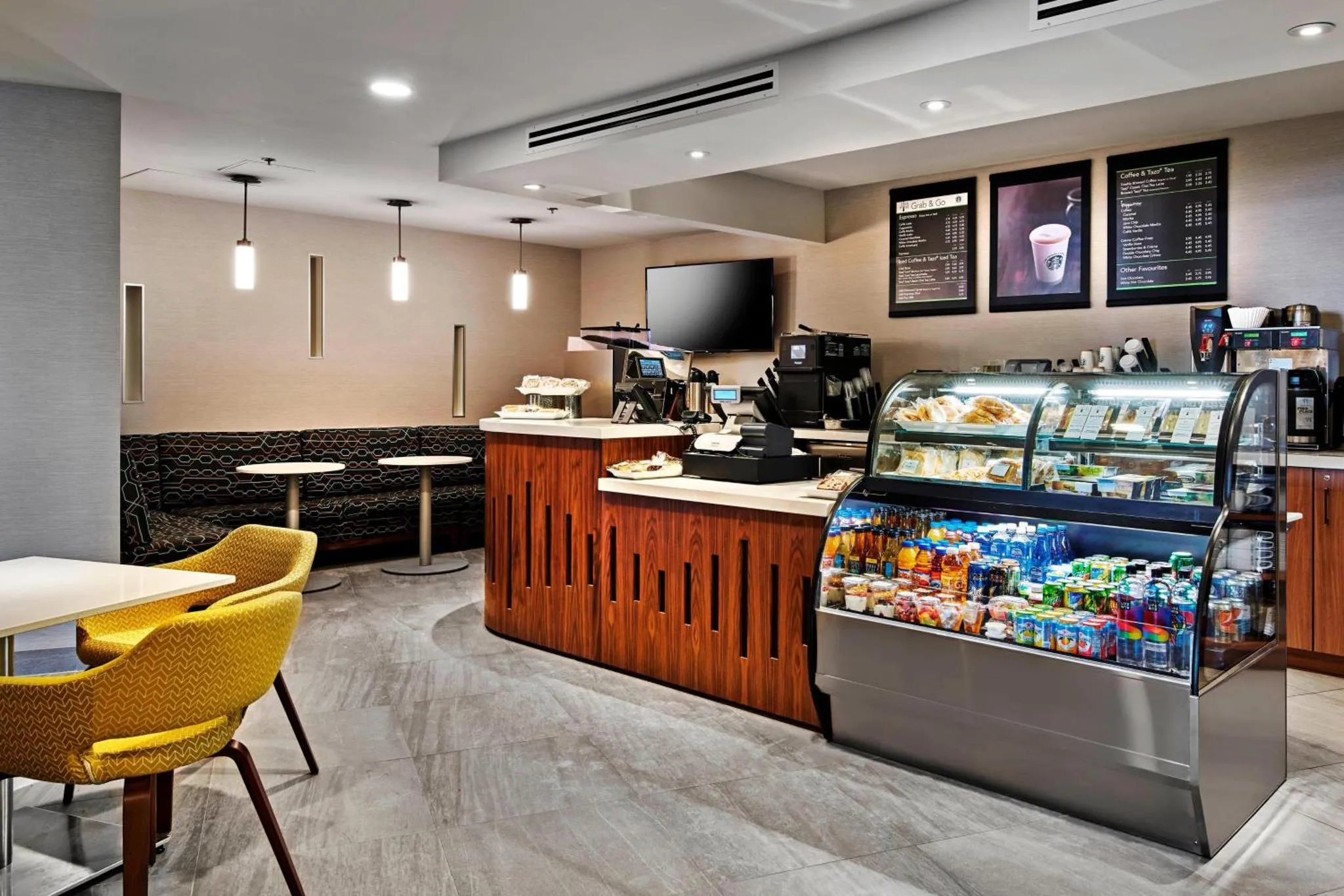 Un comptoir de café propose des pâtisseries et des boissons dans un espace lumineux et moderne.