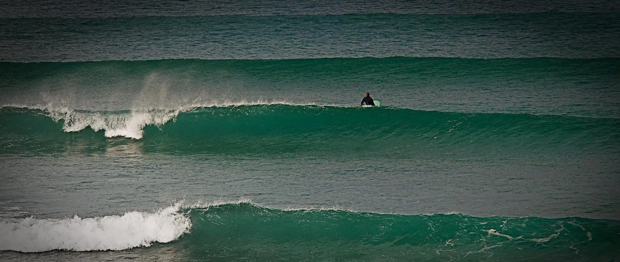 Une personne surfe sur une vague dans une mer agitée.