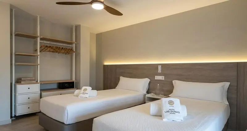 Une chambre lumineuse avec deux lits simples et une décoration sobre.