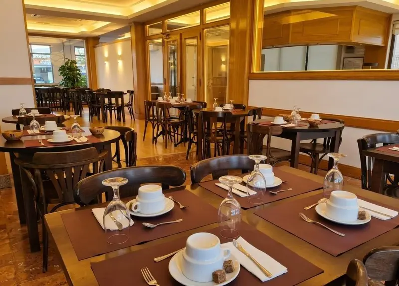 Une salle lumineuse avec des tables dressées pour le service.