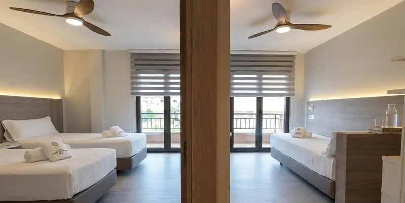 Chambre lumineuse avec deux lits simples et vue sur l'extérieur.
