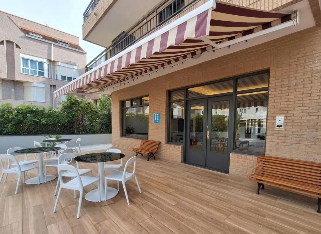 Terrasse ombragée avec tables et chaises en plastique.