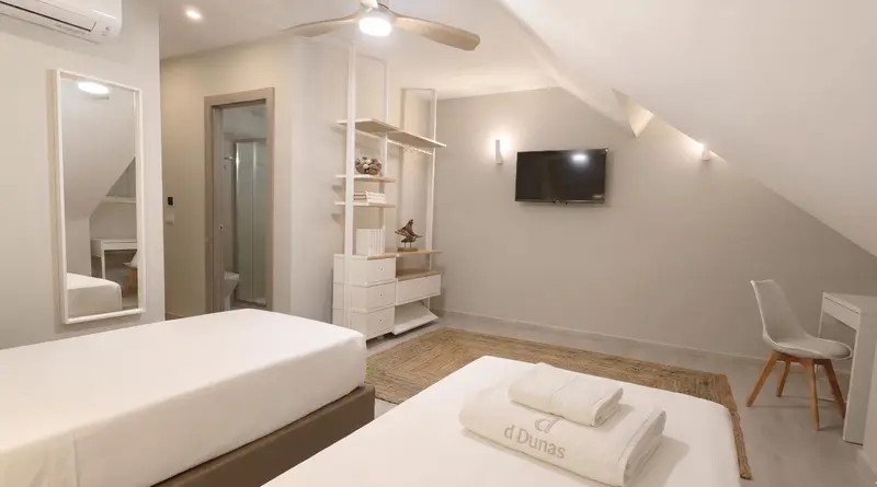 Une chambre lumineuse avec deux lits simples et un bureau.