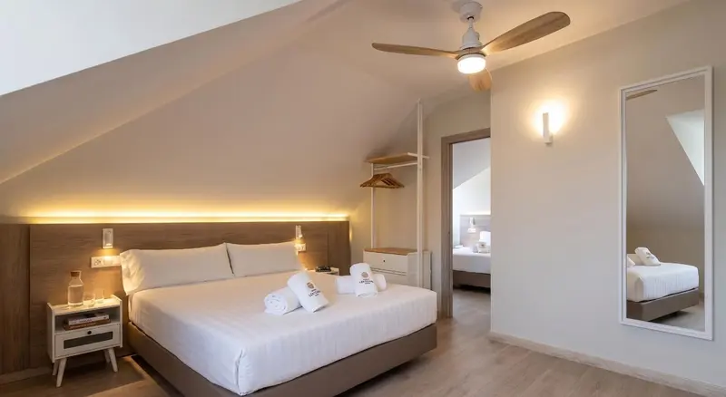 Une chambre lumineuse avec un lit double et un espace nuit attenant.