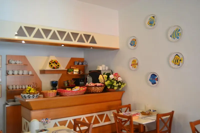 Un comptoir de buffet garni de fruits et de viennoiseries se trouve dans une salle lumineuse décorée de motifs marins.