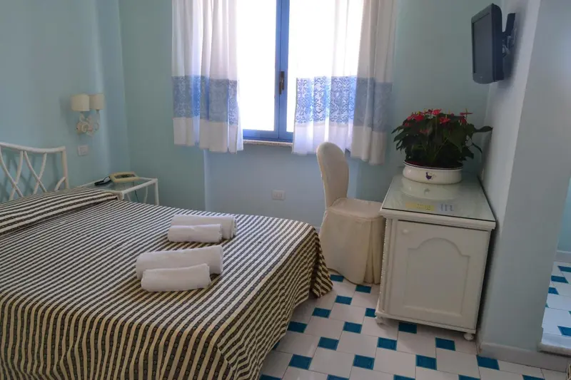 Une chambre lumineuse avec un lit recouvert d'une couverture rayée et une fenêtre décorée de rideaux.