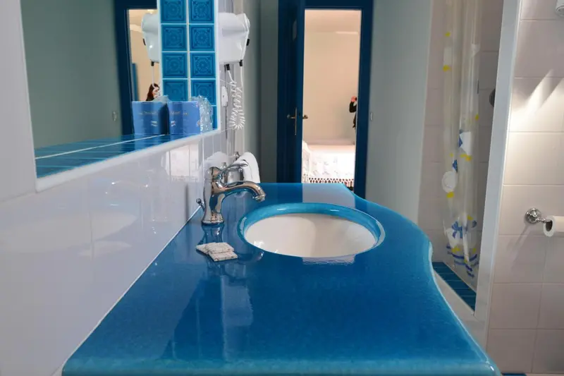 Un lavabo bleu turquoise se trouve dans une salle de bain carrelée de blanc.