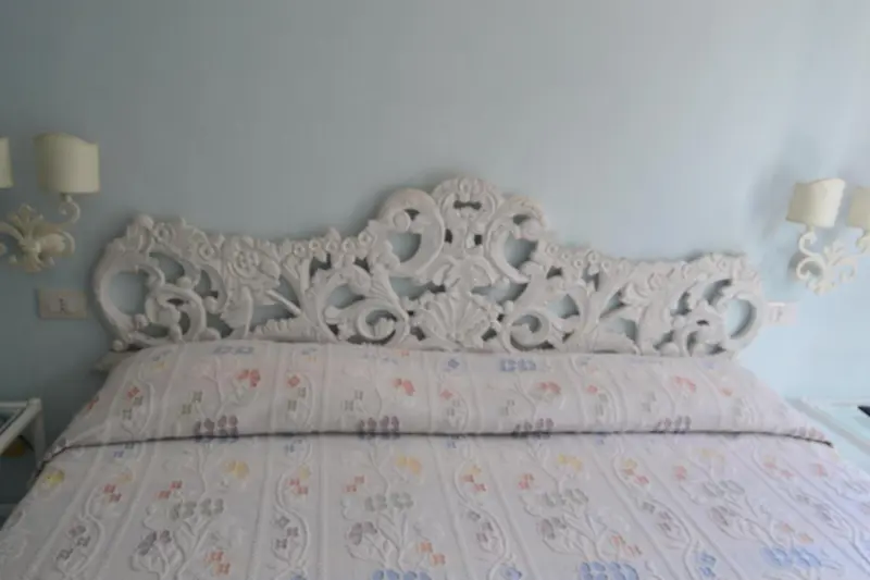 Un lit avec une tête de lit sculptée et des lampes murales.
