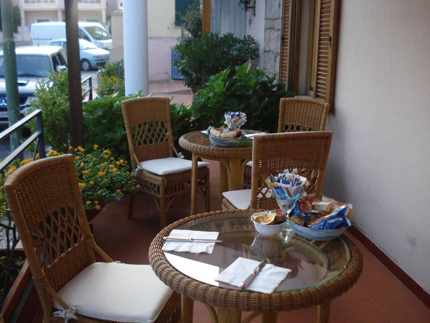 Tables et chaises en osier sur une terrasse ombragée avec des plateaux de nourriture.