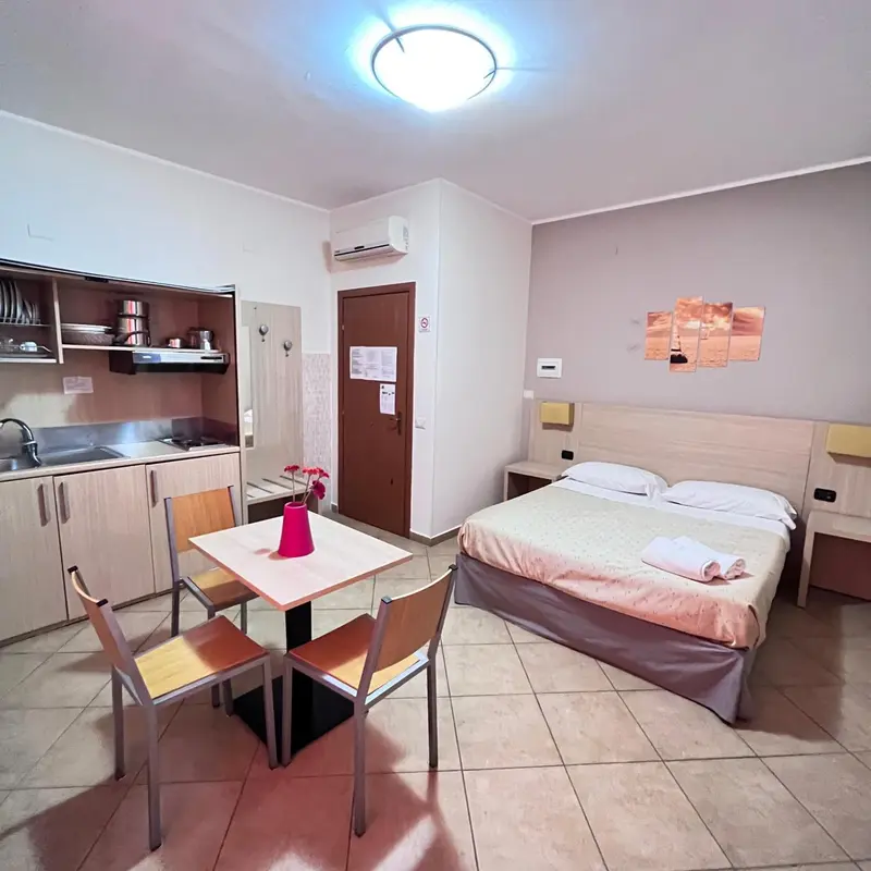 Une kitchenette et un coin repas s'ouvrent sur une chambre avec un lit.