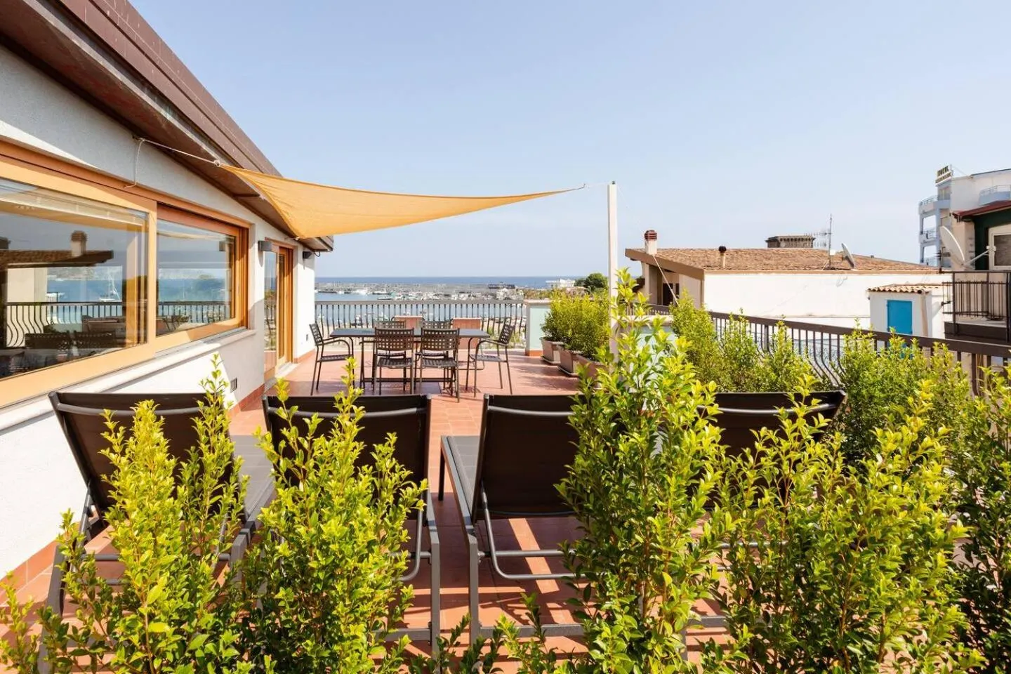 Terrasse aménagée avec mobilier de jardin et vue sur la mer.
