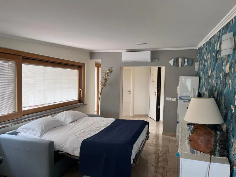 Une chambre lumineuse avec un lit fait et une décoration marine.