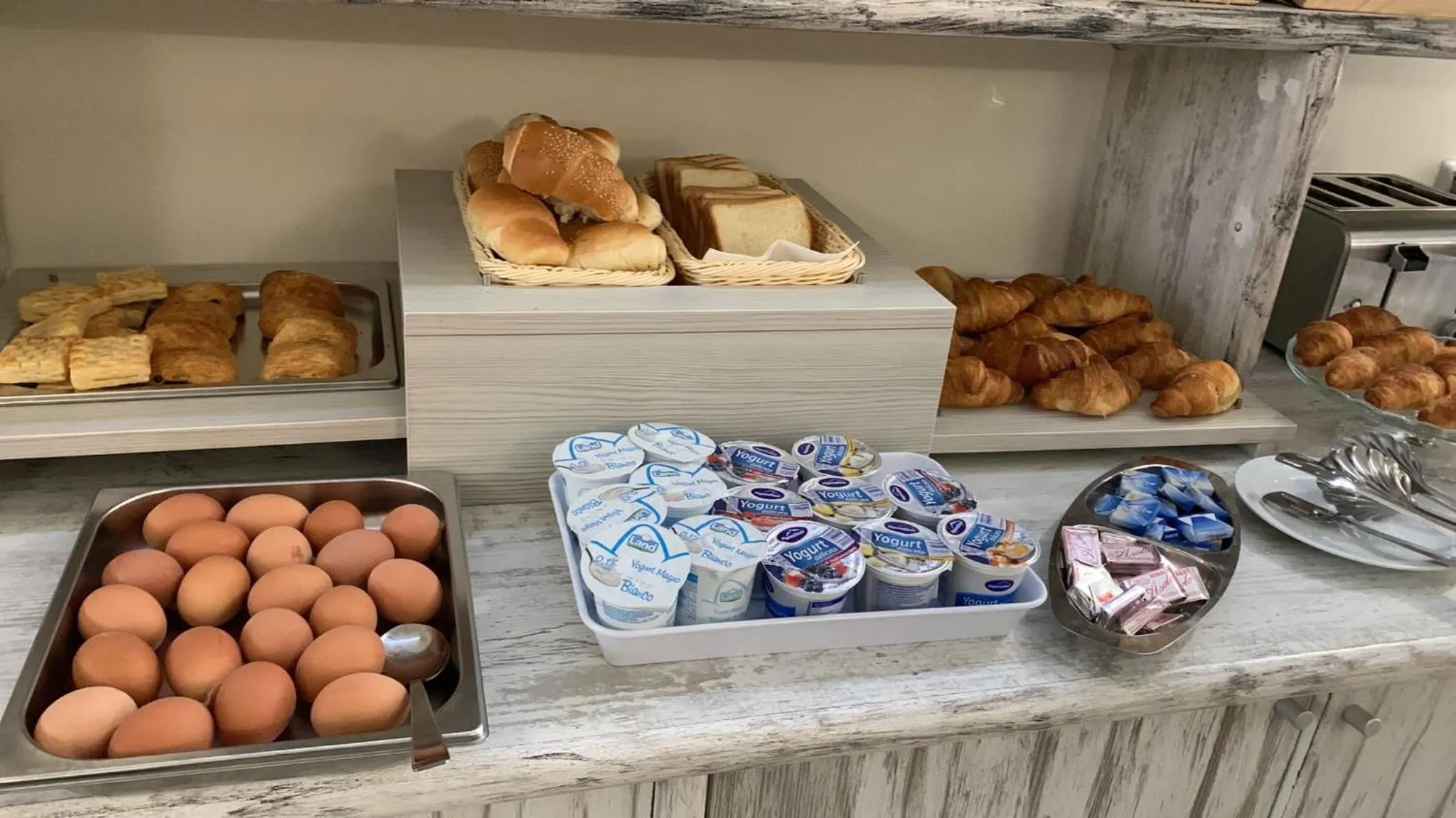 Un buffet propose des viennoiseries, des œufs et des produits laitiers.