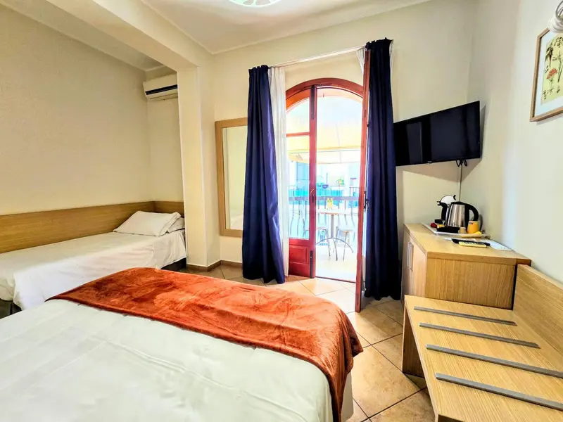 Une chambre avec deux lits et un accès à une terrasse.