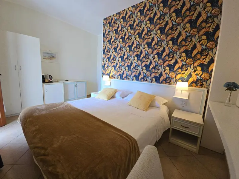 Une chambre lumineuse avec un grand lit et un mur décoré.