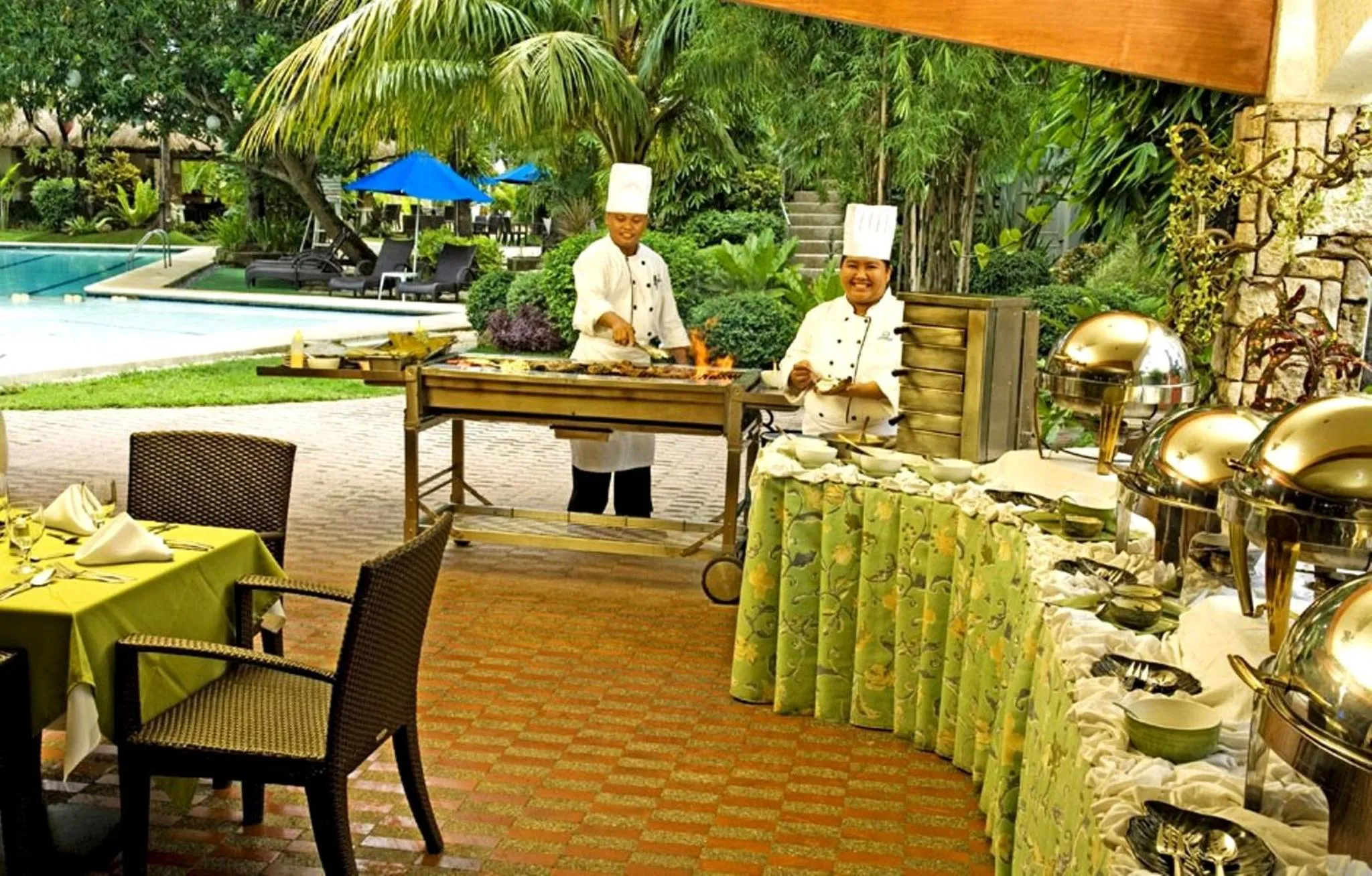Préparation de plats sur un barbecue en extérieur près d'une piscine.