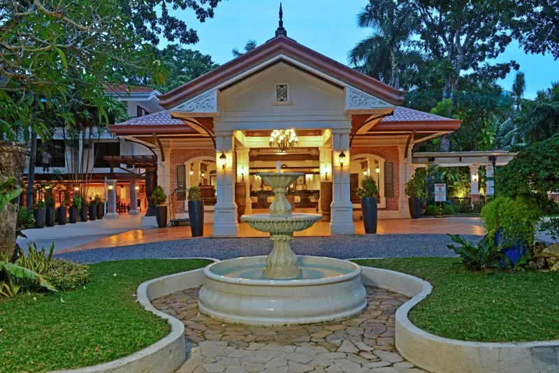 Façade d'un bâtiment avec une fontaine et un hall d'entrée éclairé.