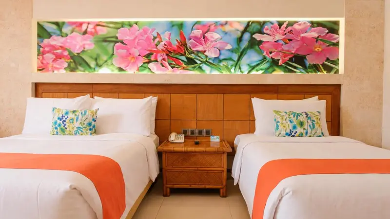 Une chambre avec deux lits simples et une décoration florale au mur.