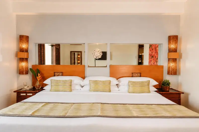 Une chambre lumineuse avec un grand lit recouvert d'une courtepointe décorative.