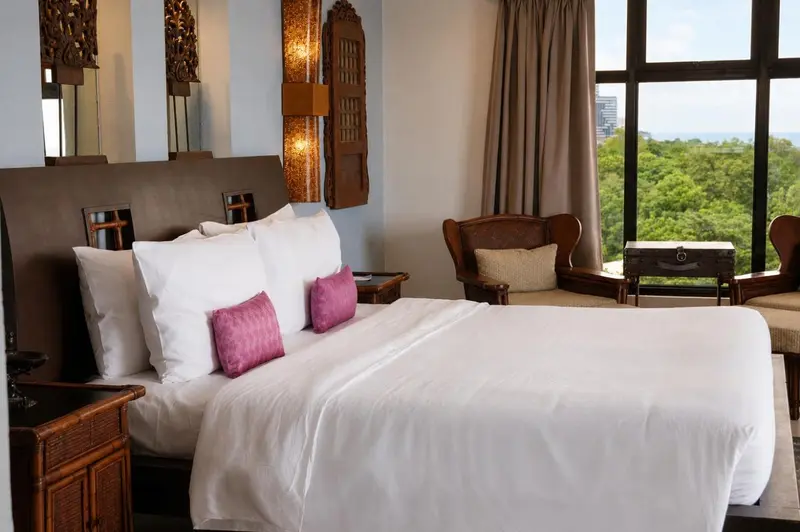 Une chambre lumineuse avec un grand lit et un coin salon près de la fenêtre.