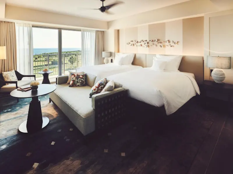 Une chambre lumineuse avec un grand lit et un coin salon donnant sur la mer.