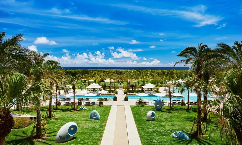 Vue aérienne d'un complexe hôtelier avec piscine et végétation tropicale.