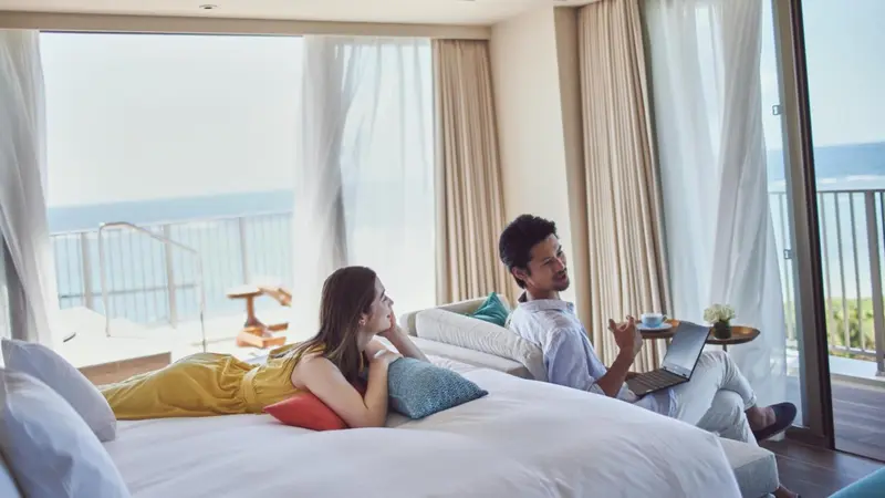 Un couple se détend dans une chambre lumineuse avec vue sur la mer.