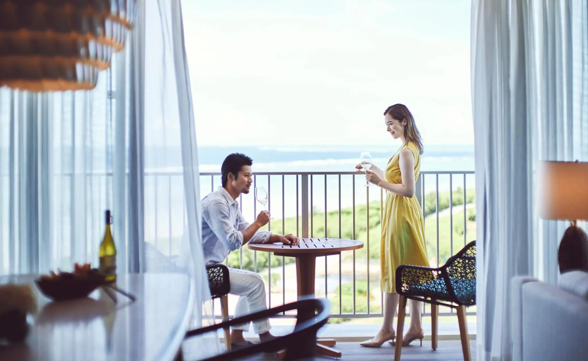 Un couple déguste des boissons sur une terrasse avec vue sur la mer.
