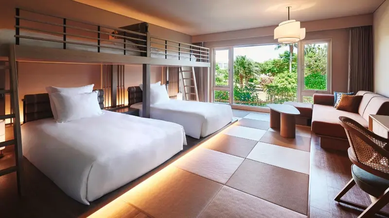 Une chambre lumineuse avec lits superposés et canapé face à une grande baie vitrée.