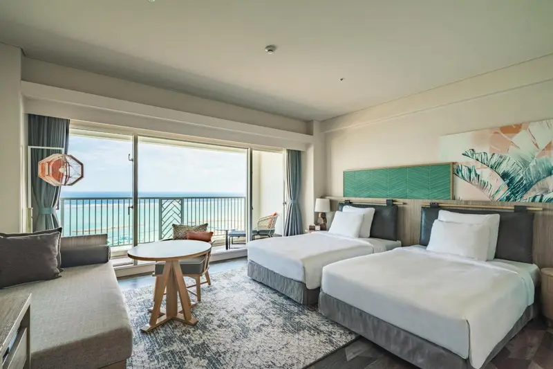 Chambre lumineuse avec deux lits simples et vue sur la mer.