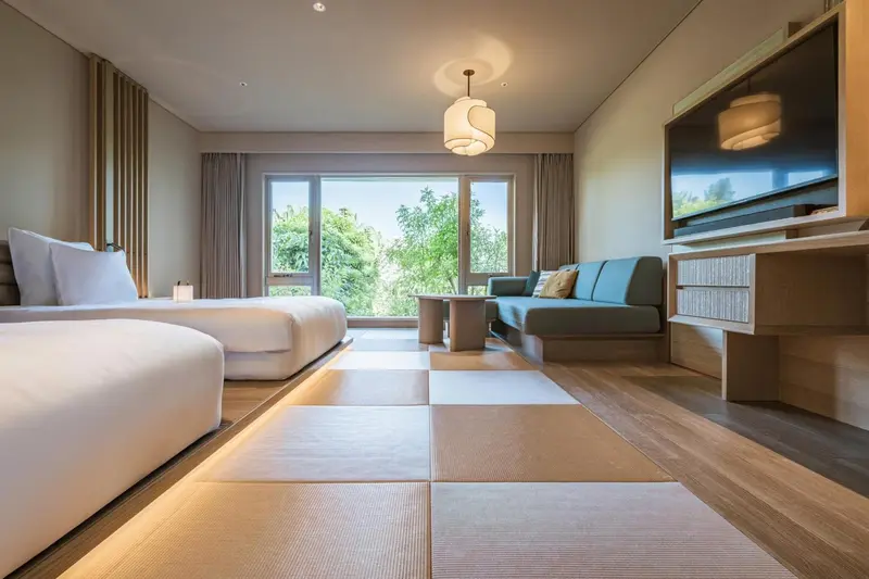Une chambre lumineuse avec un lit et un canapé face à une grande fenêtre.