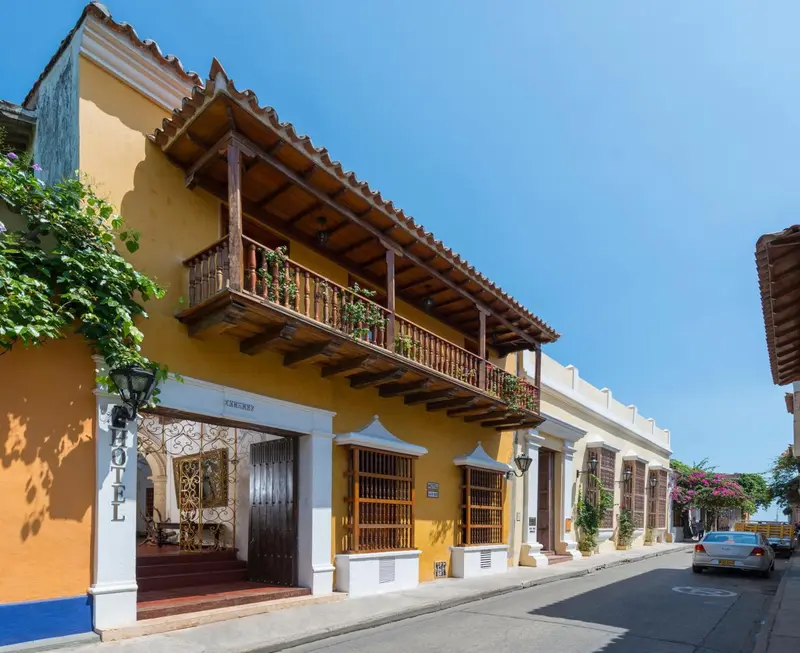 Facade jaune d'un bâtiment avec des balcons en bois et des fenêtres grillagées.