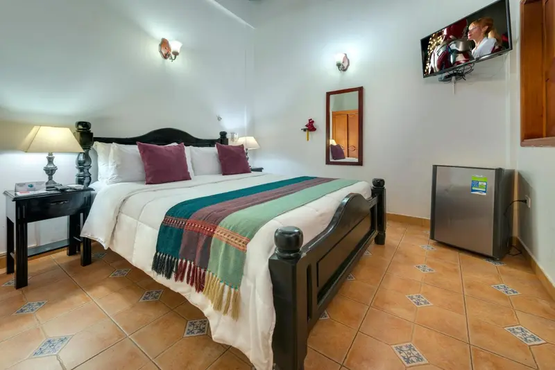 Une chambre lumineuse avec un grand lit recouvert d'une courtepointe colorée.