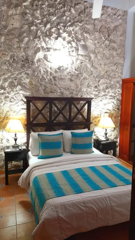 Une chambre avec un lit double et un mur texturé.