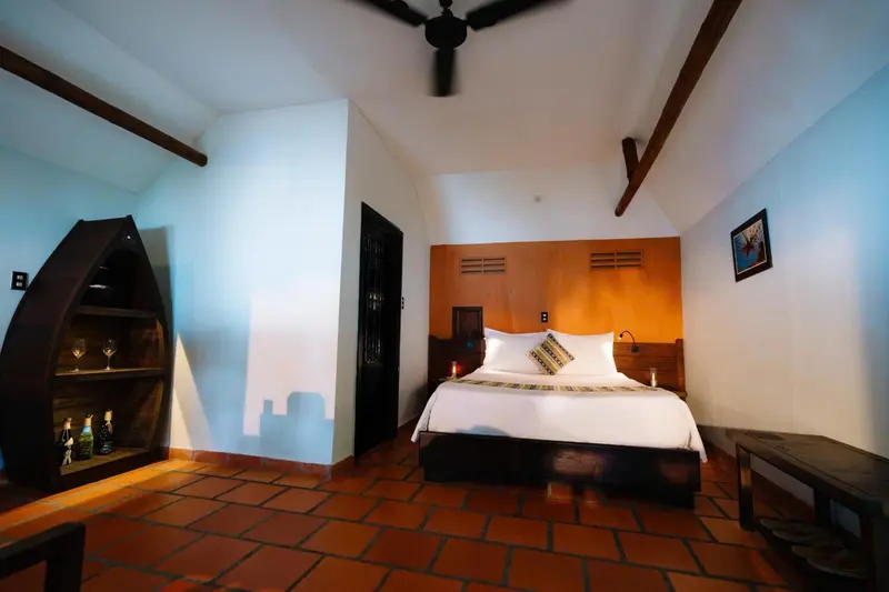 Une chambre lumineuse avec un lit double et un coin salon.