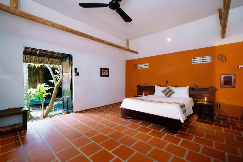 Une chambre lumineuse avec un lit double et un accès à une cour verdoyante.