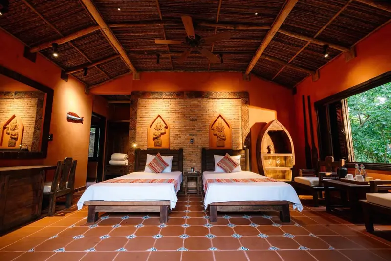 Chambre aux murs orange avec deux lits simples et une décoration murale sculptée.