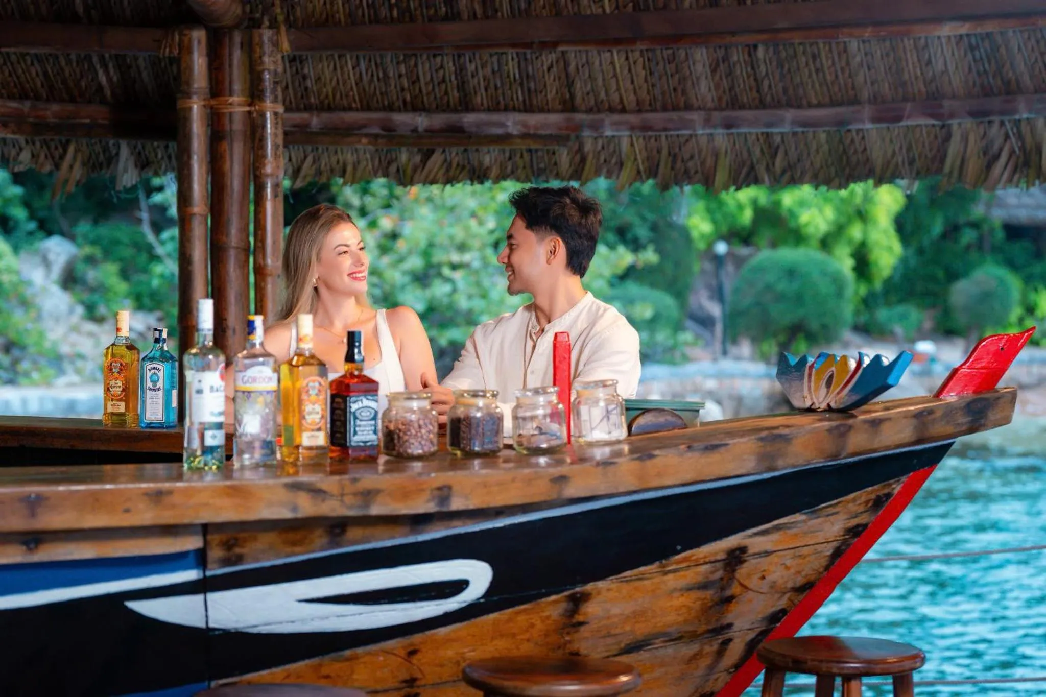 Un couple souriant est assis au comptoir d'un bar en bord de mer.