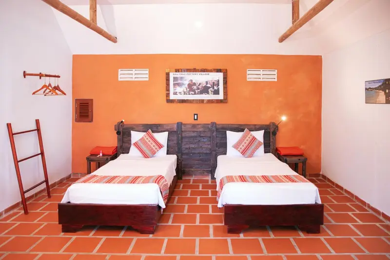 Une chambre aux murs orange avec deux lits simples et une décoration locale.
