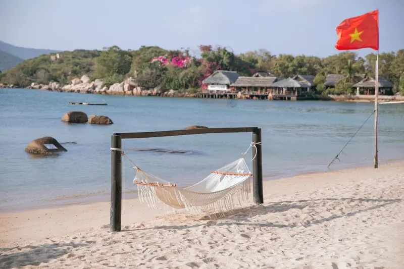 Un hamac est suspendu sur une plage de sable fin face à une mer turquoise.